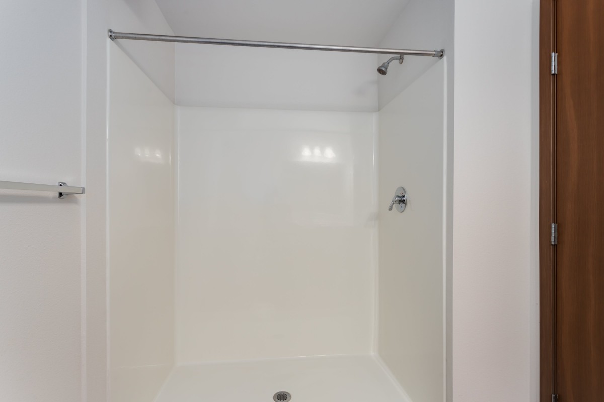 A minimalist white shower setup in a bathroom.