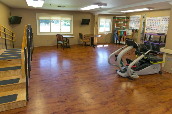 An empty gym room featuring exercise equipment and wooden flooring.