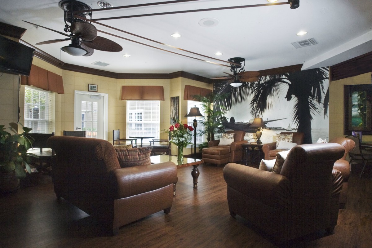 A cozy living room with leather chairs, wood flooring, and abundant natural light.