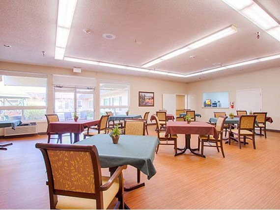 A spacious dining room with neatly arranged tables and chairs, featuring bright lighting and a welcoming atmosphere.