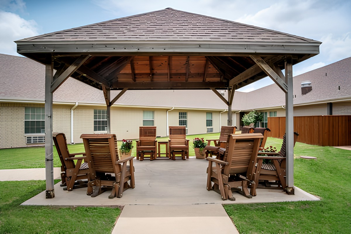 An inviting outdoor gazebo with wooden seating arrangement on a patio.