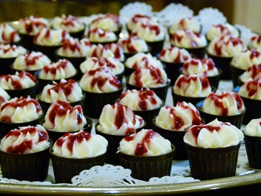 Delicious mini cupcakes topped with whipped cream and raspberry sauce, perfect for any celebration.