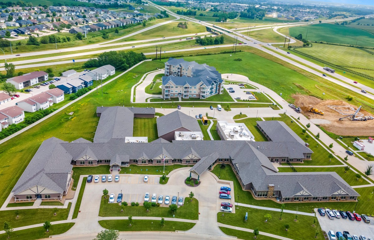 Aerial view of suburban infrastructure with buildings and roads surrounded by greenery.