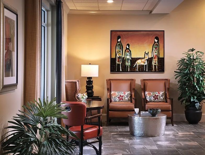 A cozy waiting room with comfortable seating, a table, and artwork on the wall.