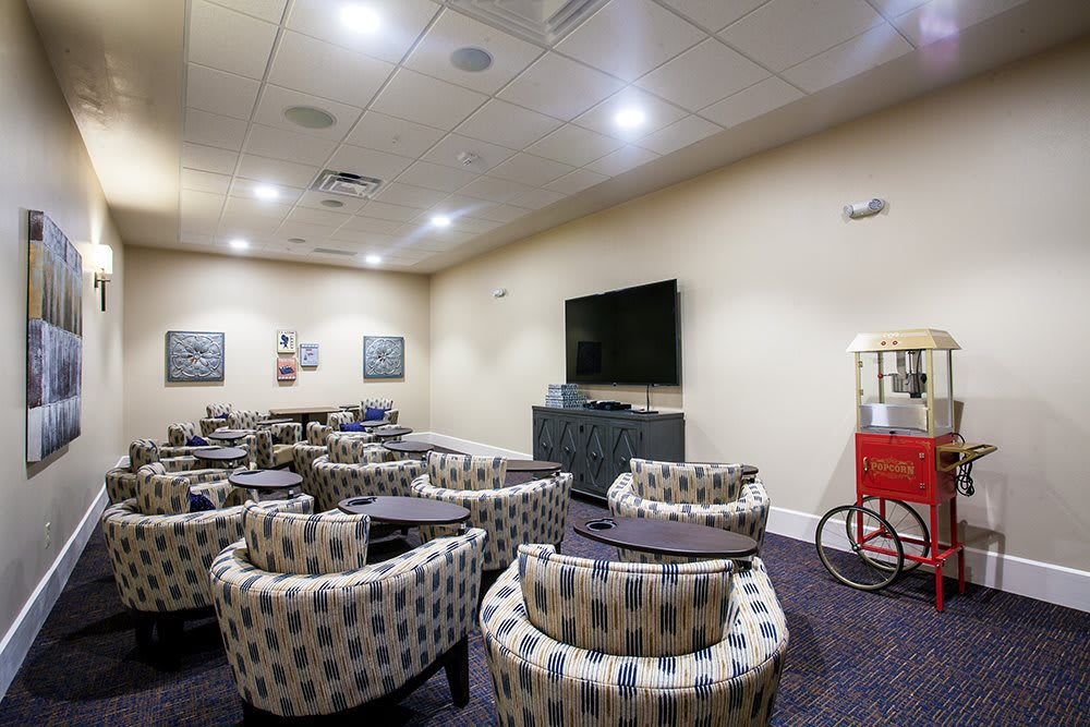 A cozy lounge area with numerous chairs, a large television, and a popcorn machine.