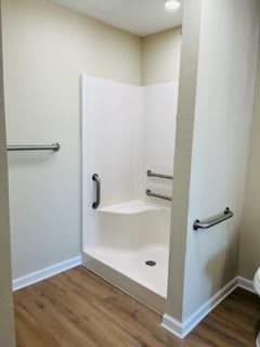 An accessible bathroom shower equipped with grab bars and a built-in seat.