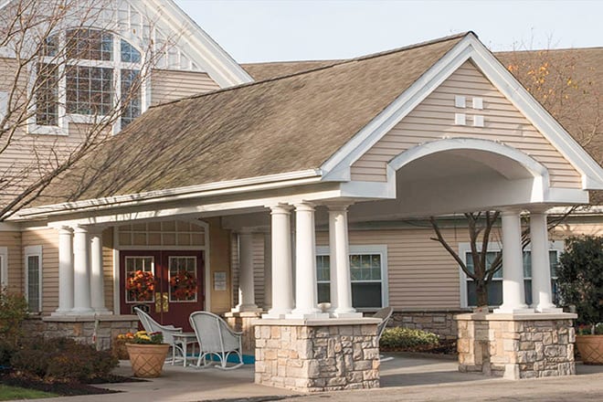 A welcoming entrance to a residential building featuring a porch with columns.