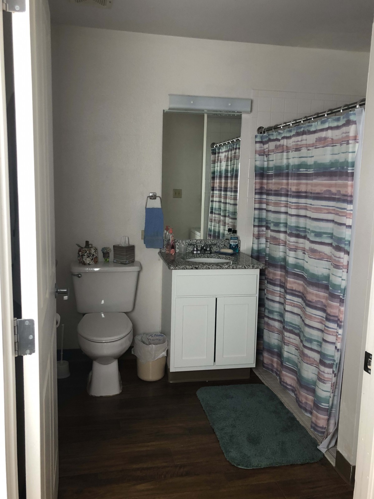 A small bathroom with a toilet, sink, and colorful shower curtain.
