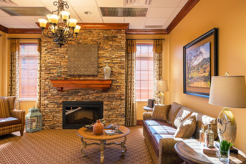 A cozy living room with a stone fireplace and elegant chandelier.
