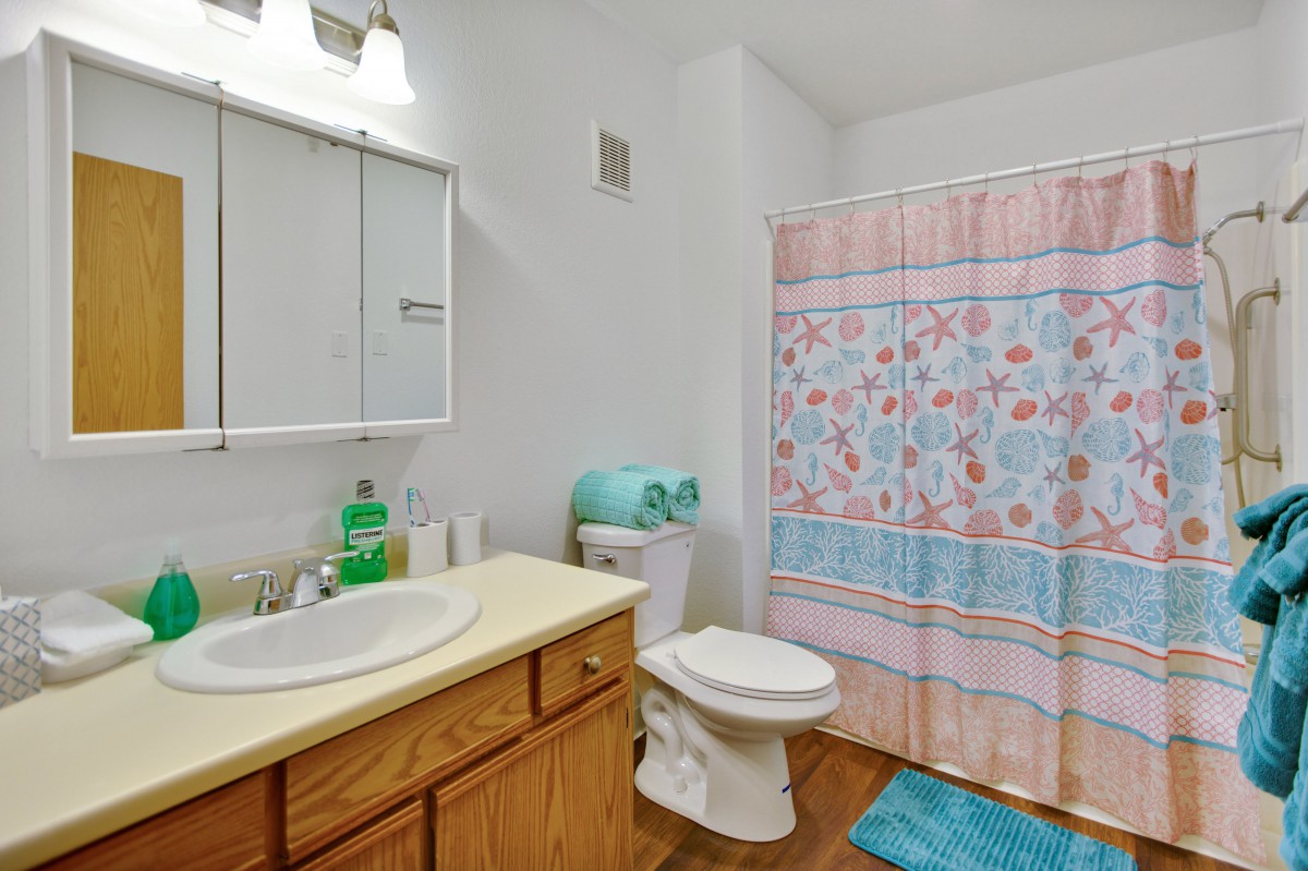 A clean and organized bathroom with a colorful shower curtain.