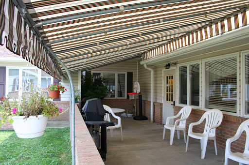 A serene outdoor patio featuring a covered area with chairs and a grill, perfect for relaxation.