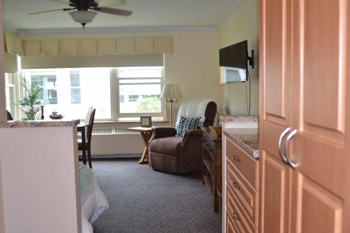 A cozy bedroom with a recliner chair, television, and large windows.
