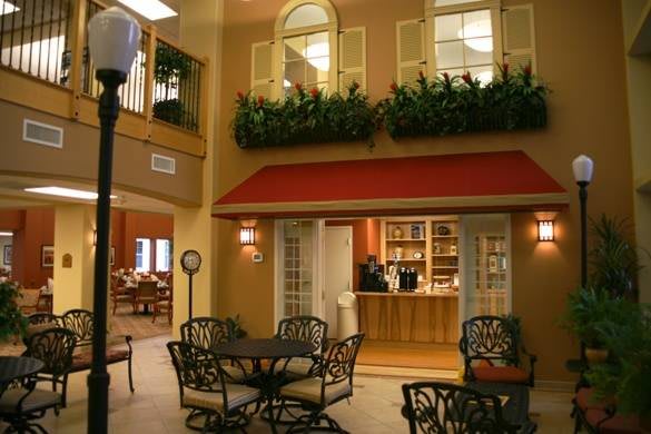 An indoor cafe with seating arrangements, decorative plants, and warm lighting.