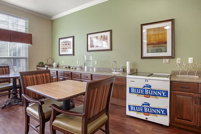 A dining room with wooden furniture, artwork on the walls, and a small freezer in the corner.