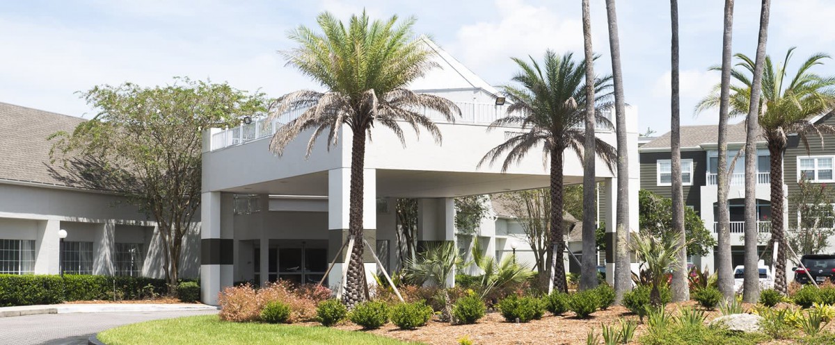 A modern building surrounded by palm trees and landscaped gardens.