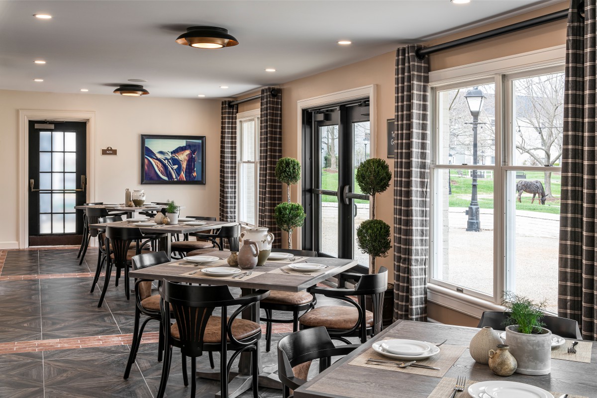 A modern restaurant dining area with neatly arranged tables and chairs, featuring large windows that let in natural light.