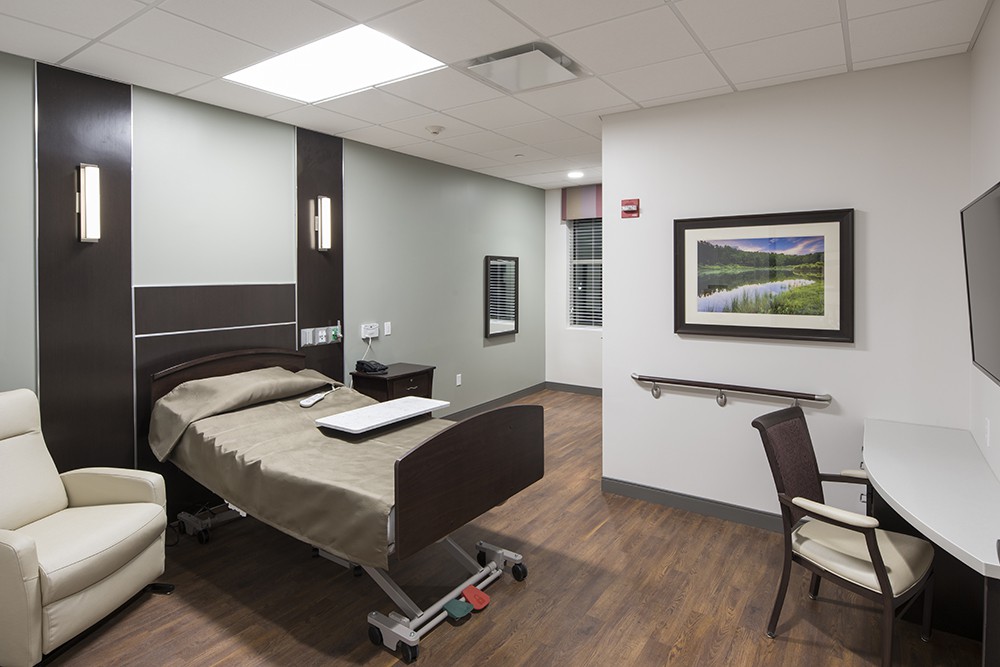 A modern hospital room featuring a bed and clean, minimalist design.
