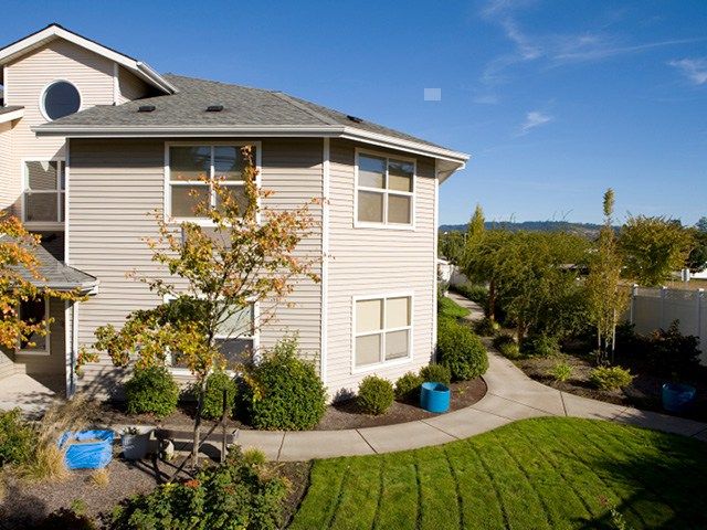 A well-maintained apartment complex with lush landscaping and a sunny sky.