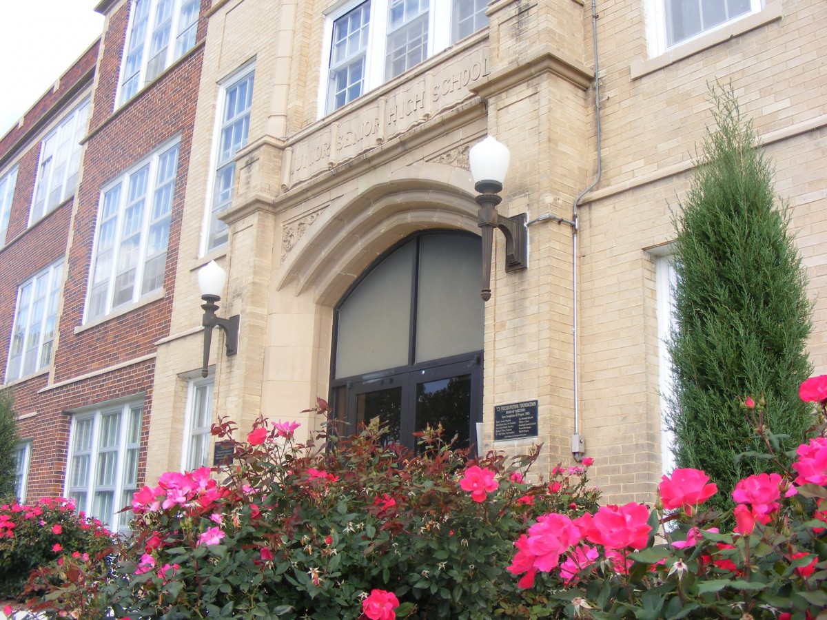 A building entrance surrounded by blooming pink roses.