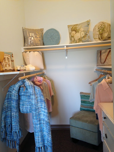 A neatly organized closet featuring hanging clothes and decorative pillows on the shelves.