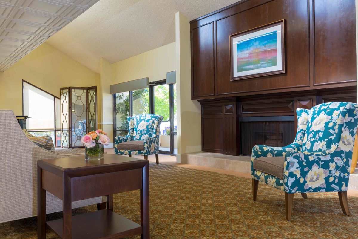 A cozy living room with a fireplace, armchairs, and a coffee table.