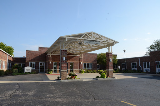A modern medical facility entrance with a structured canopy and well-maintained landscaping.