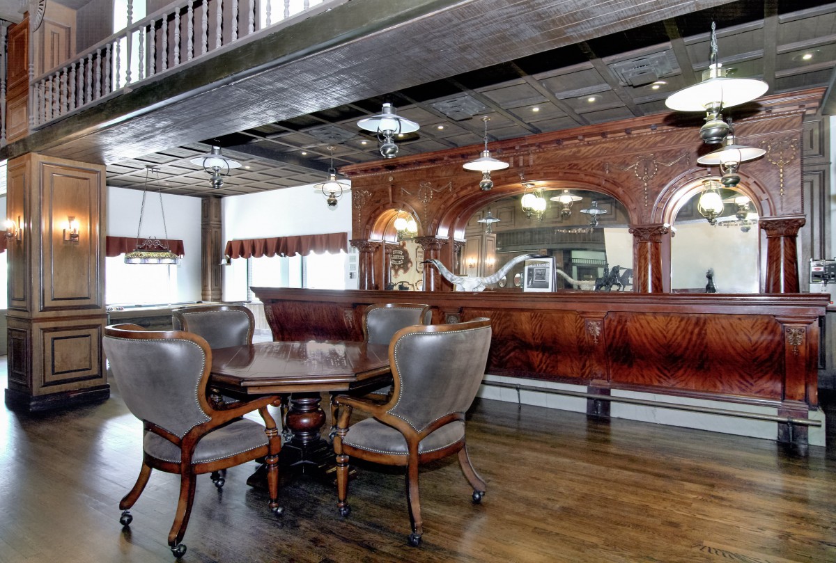 A vintage-style room featuring an elegant wooden bar and antique dining furniture.