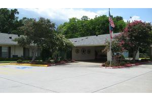 A small building with an entrance surrounded by trees and a flagpole in front.