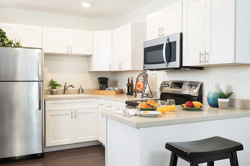 A modern kitchen featuring white cabinets and stainless steel appliances, complete with a cozy breakfast setup.