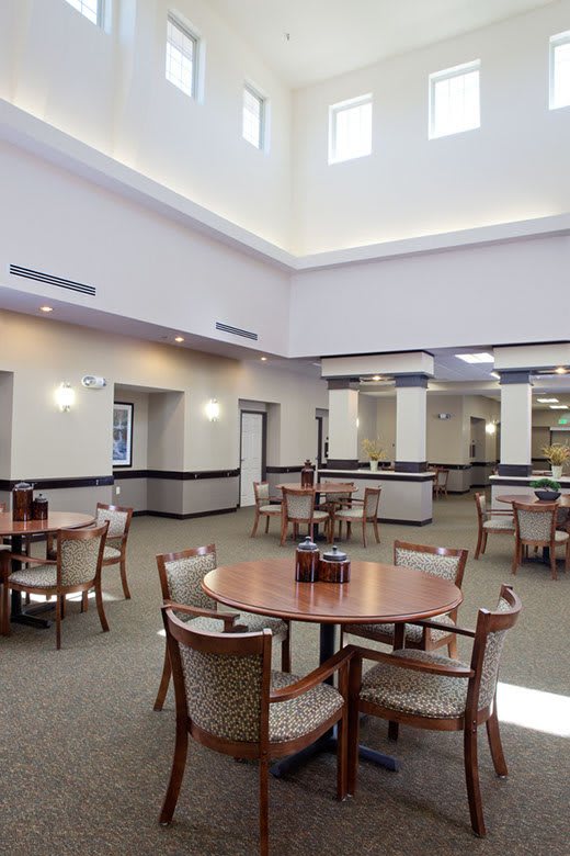 A spacious dining room with tables and chairs arranged neatly, featuring modern lighting and decor.