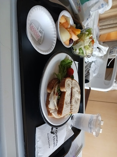 A meal tray featuring a sandwich, salad, and fruit.