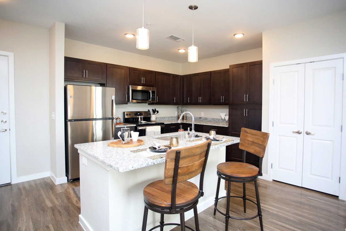 A modern kitchen featuring a central island with bar stools and stainless steel appliances.
