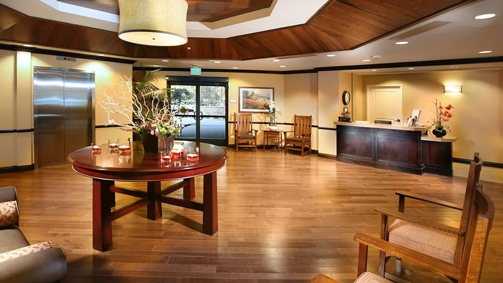 A spacious lobby area with wooden flooring, elegant furniture, and ambient lighting.