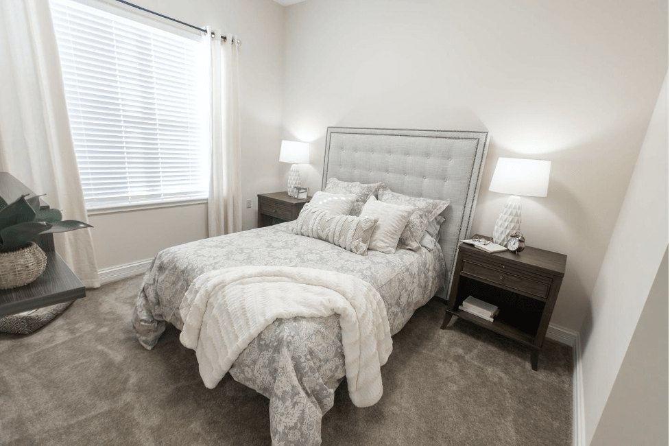 A cozy bedroom with a neatly made bed, flanked by nightstands and lamps.