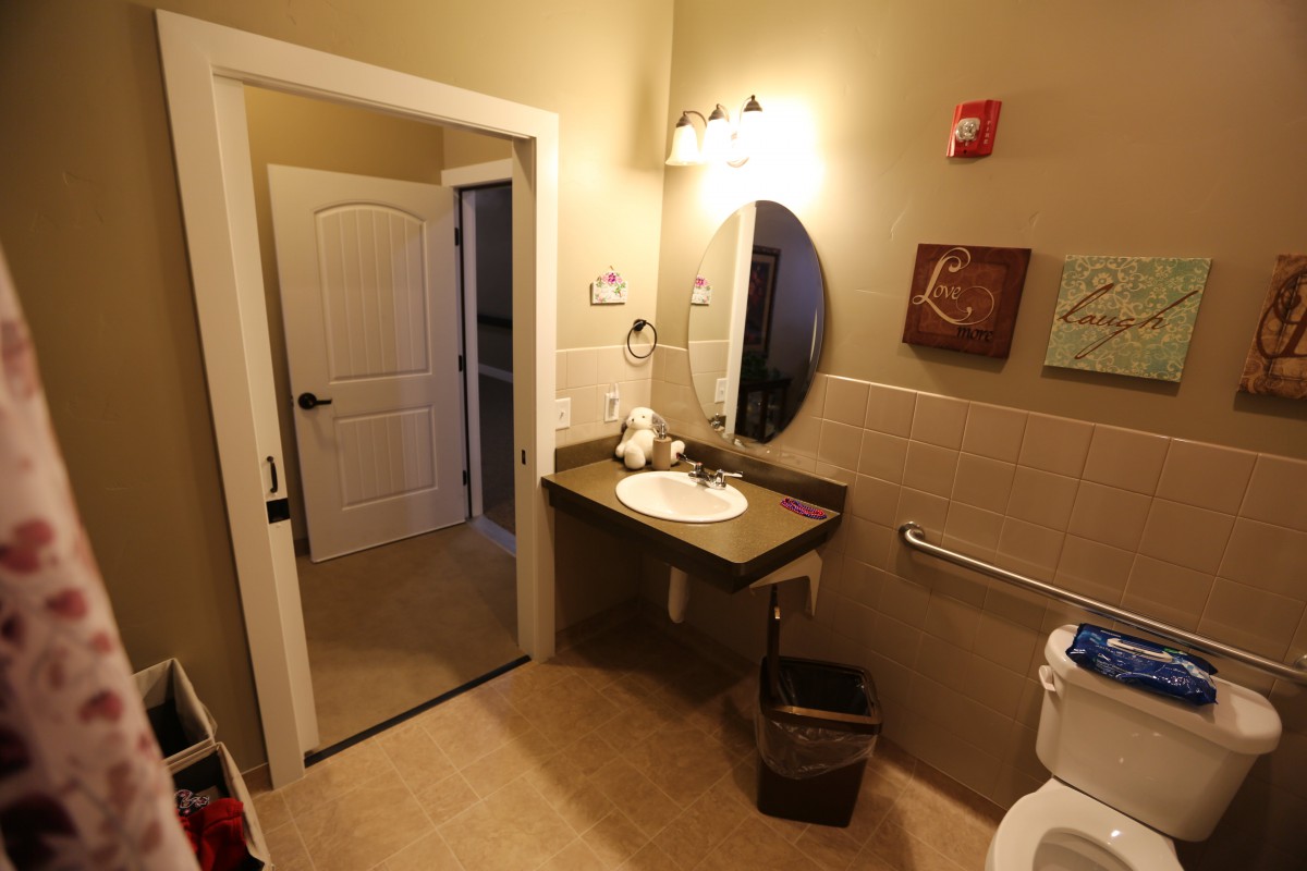 A well-lit bathroom featuring a sink, mirror, and tasteful wall art.