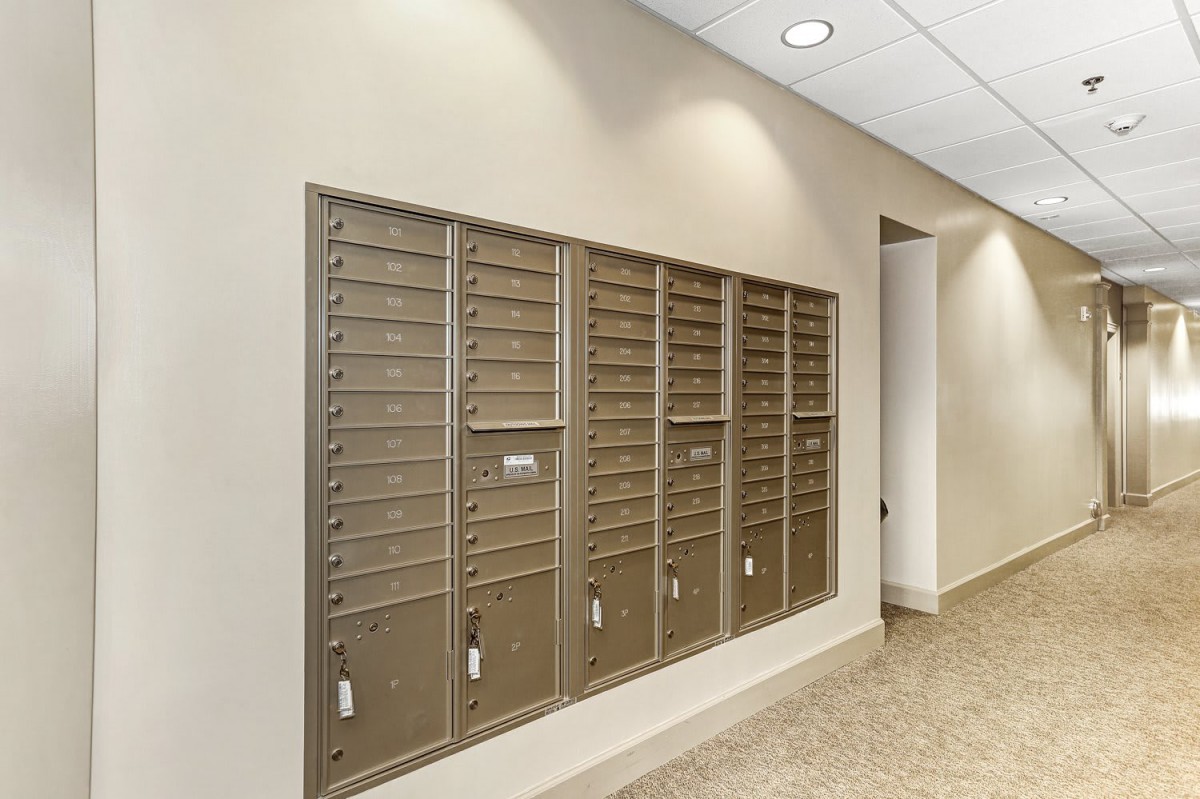 A row of metal mailboxes inside a building hallway.