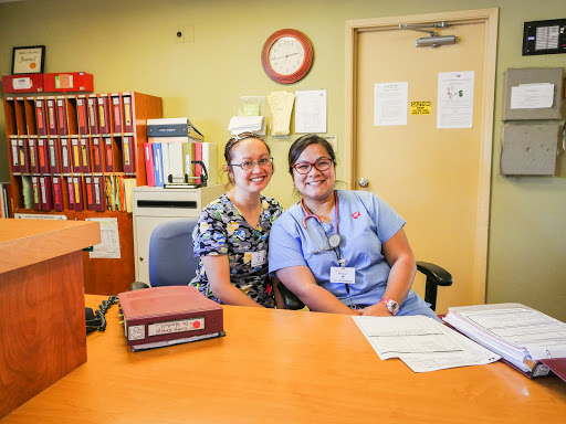 Two friendly staff members smile for the camera in a healthcare office setting.
