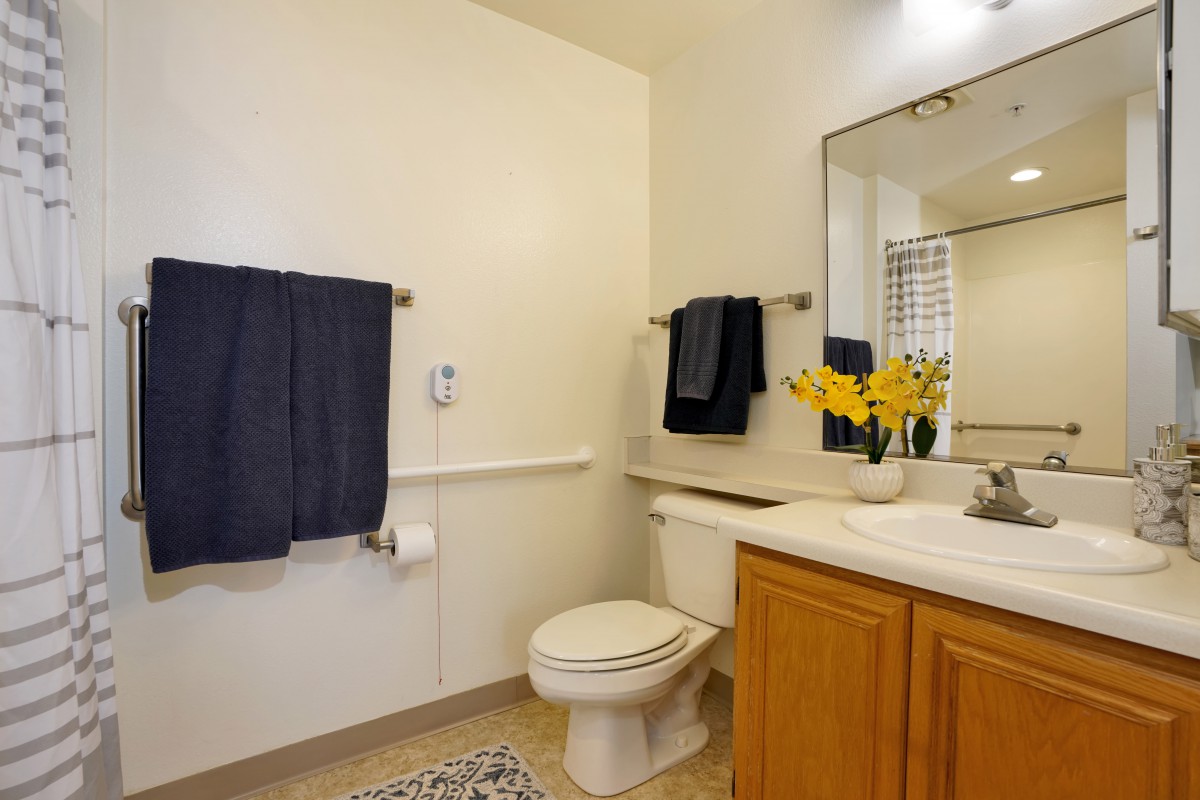 A clean and organized bathroom with a mirror, sink, and neatly hung towels.