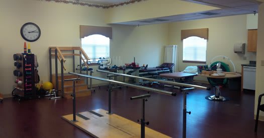 A rehabilitation room featuring parallel bars and other physical therapy equipment.