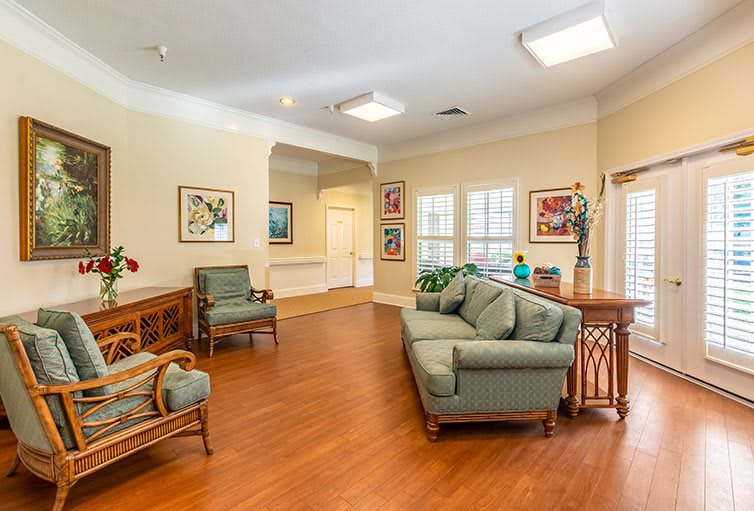 A cozy living room with couches, chairs, and artwork on the walls.