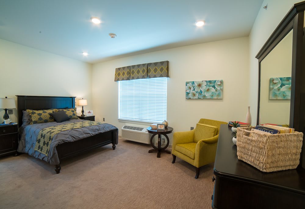 A well-lit bedroom with a bed, armchair, and decorative elements.