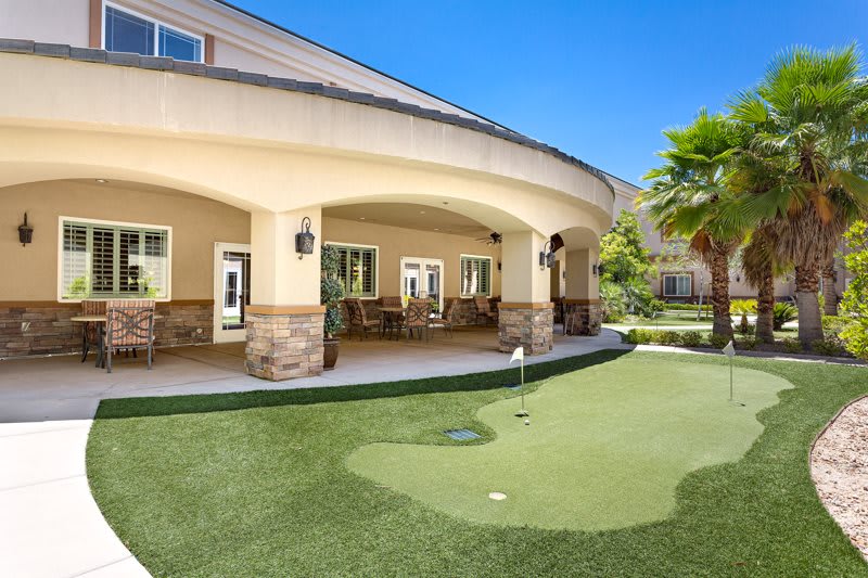 A beautifully designed outdoor patio area with a mini golf lawn under a clear blue sky.