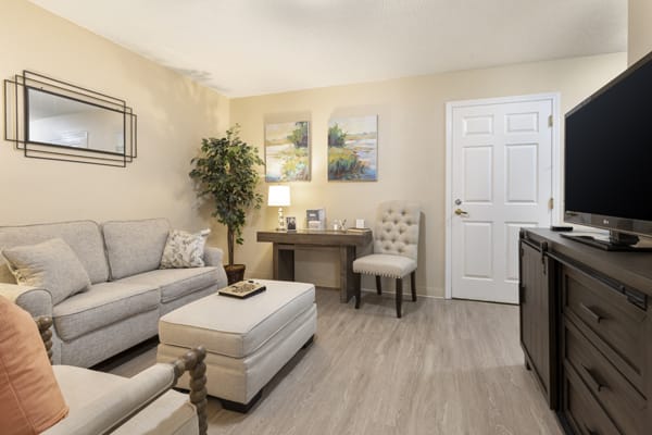 A cozy and elegantly designed living room featuring a sofa, ottoman, desk, and decorative elements.