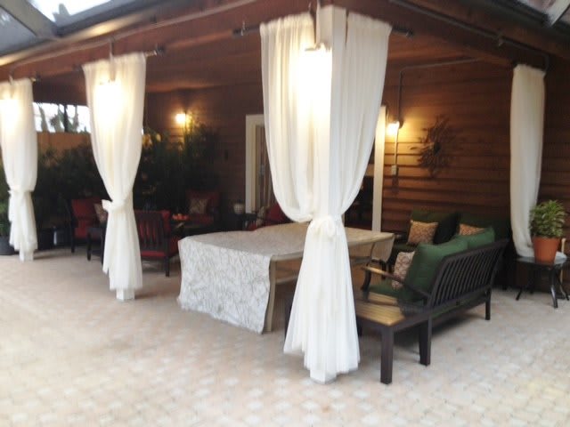 A cozy outdoor patio with curtains and seating area.
