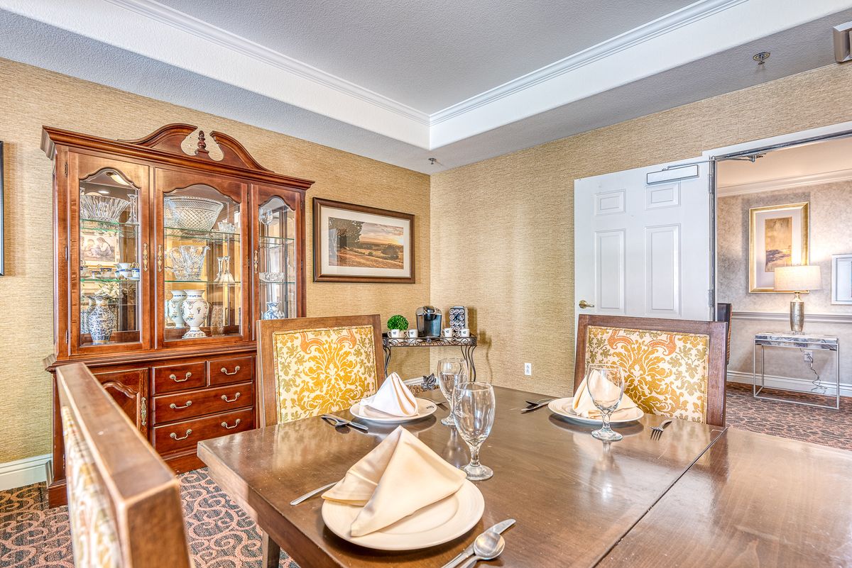 A well-decorated dining room featuring a wooden table with neatly arranged napkins and glassware, complemented by a china cabinet and tasteful decor.
