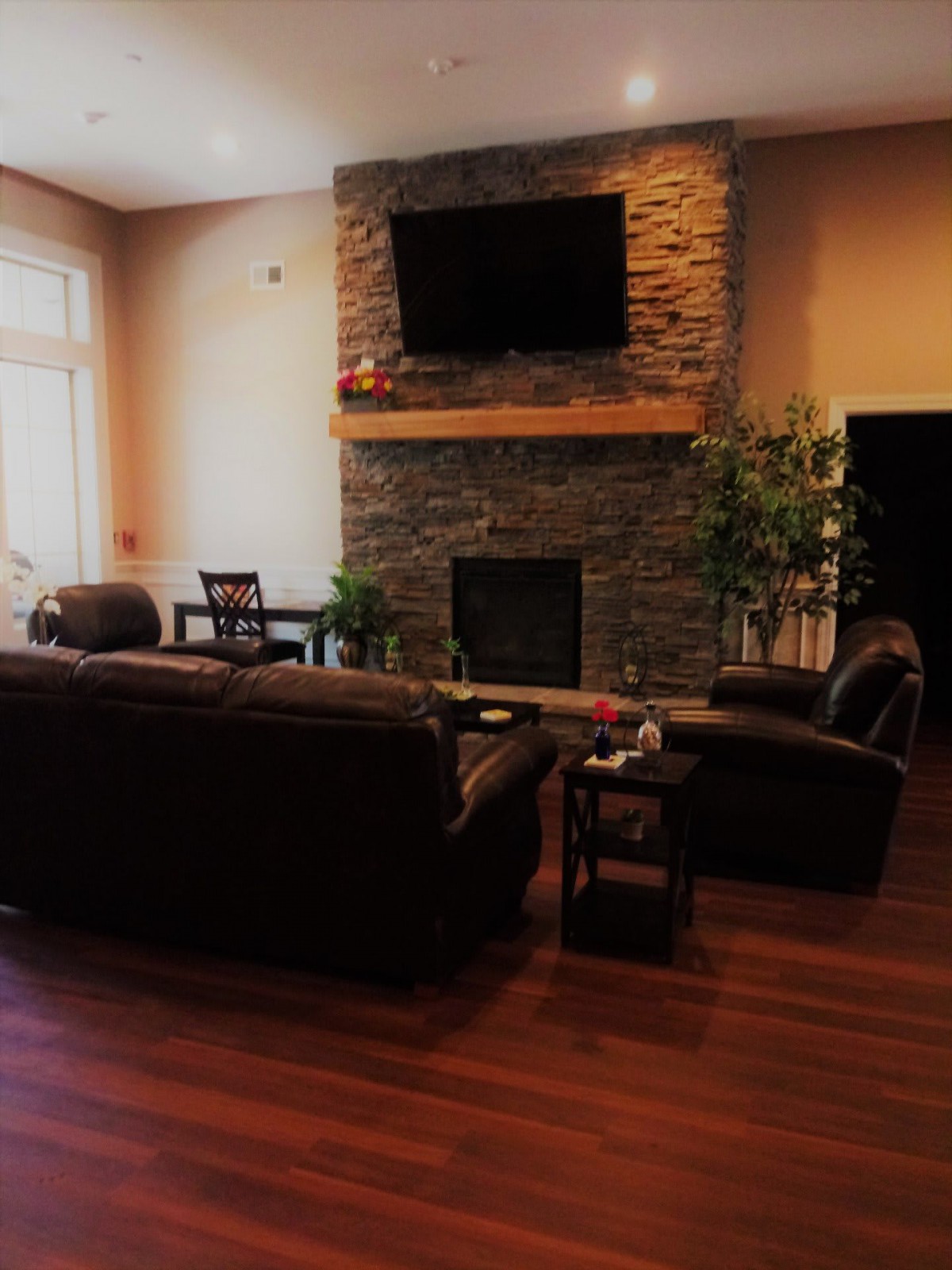A cozy living room with a stone fireplace and mounted TV.