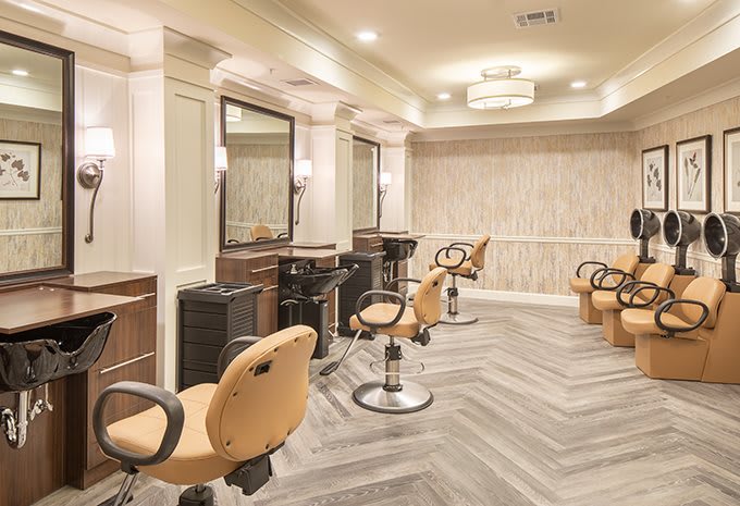 A modern hair salon interior with stylish chairs and mirrors.