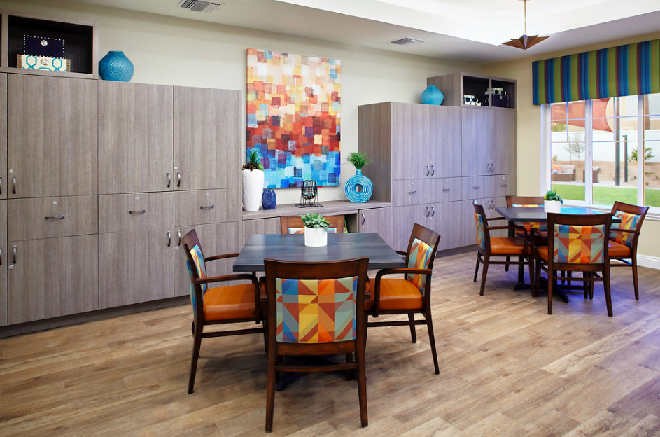 A modern dining area with colorful artwork and matching chairs.