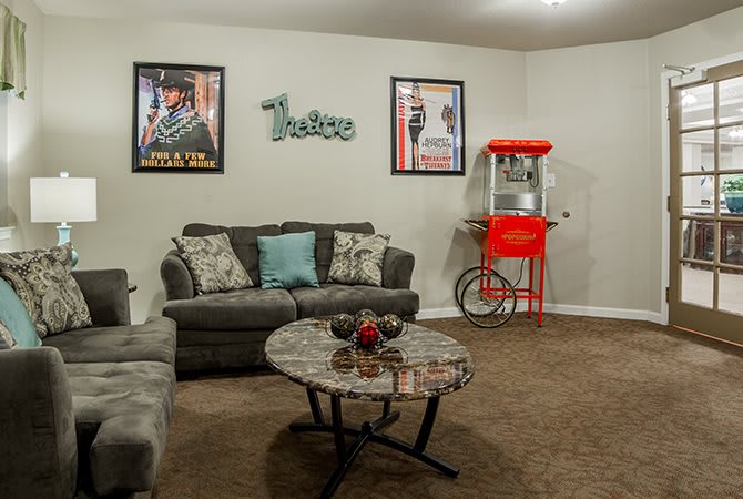 A cozy home theater setup featuring a comfortable couch, movie posters, and a classic popcorn machine.