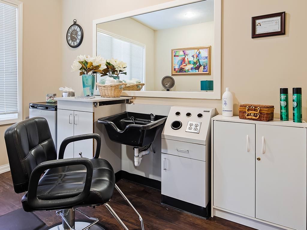 A cozy salon interior featuring a styling chair, mirror, and sink with decorative touches.